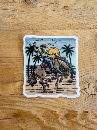 Sticker of a cowboy riding a horse with palm trees and a sunset. 