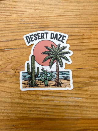 Sticker with 'Desert Daze' design featuring a cactus, palm tree, and sunset.
