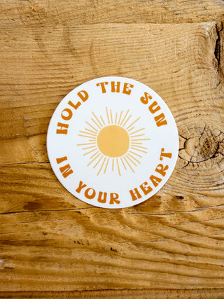 Circular sticker with 'Hold the Sun in Your Heart' text. 
