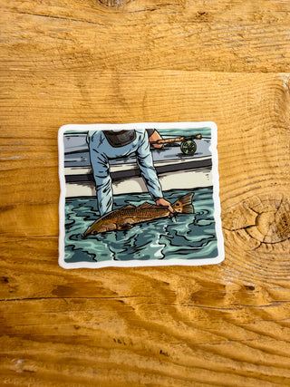 Sticker of a person releasing a redfish into the water while on the boat. 