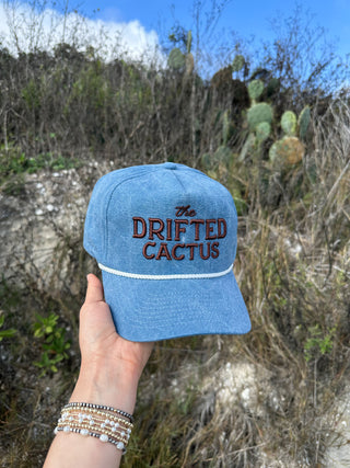 denim rope hat with brown embroidered text that says the drifted cactus. 