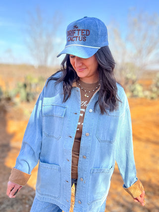 denim rope hat with brown embroidered text that says the drifted cactus. 