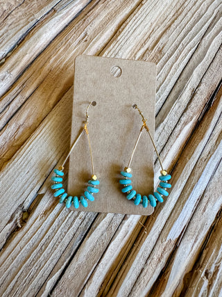 gold teardrop dangle earrings with turquoise colored beads at the bottom.