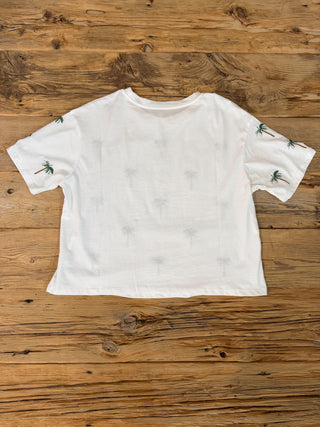 Back of White short sleeve tee with embroidered palm trees pattern. Back is plain except the back of the sleeves have the embroidered palm trees. 