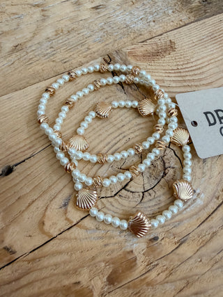 three piece stretch bracelet set. a mix of pearls, gold beads, and clam shell charms. 