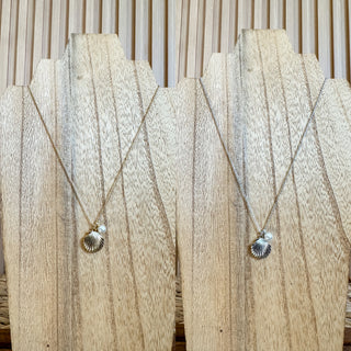 showing both colors in this necklace. one is silver and one is gold. it's a necklace with a clam shell and pearl charms. 